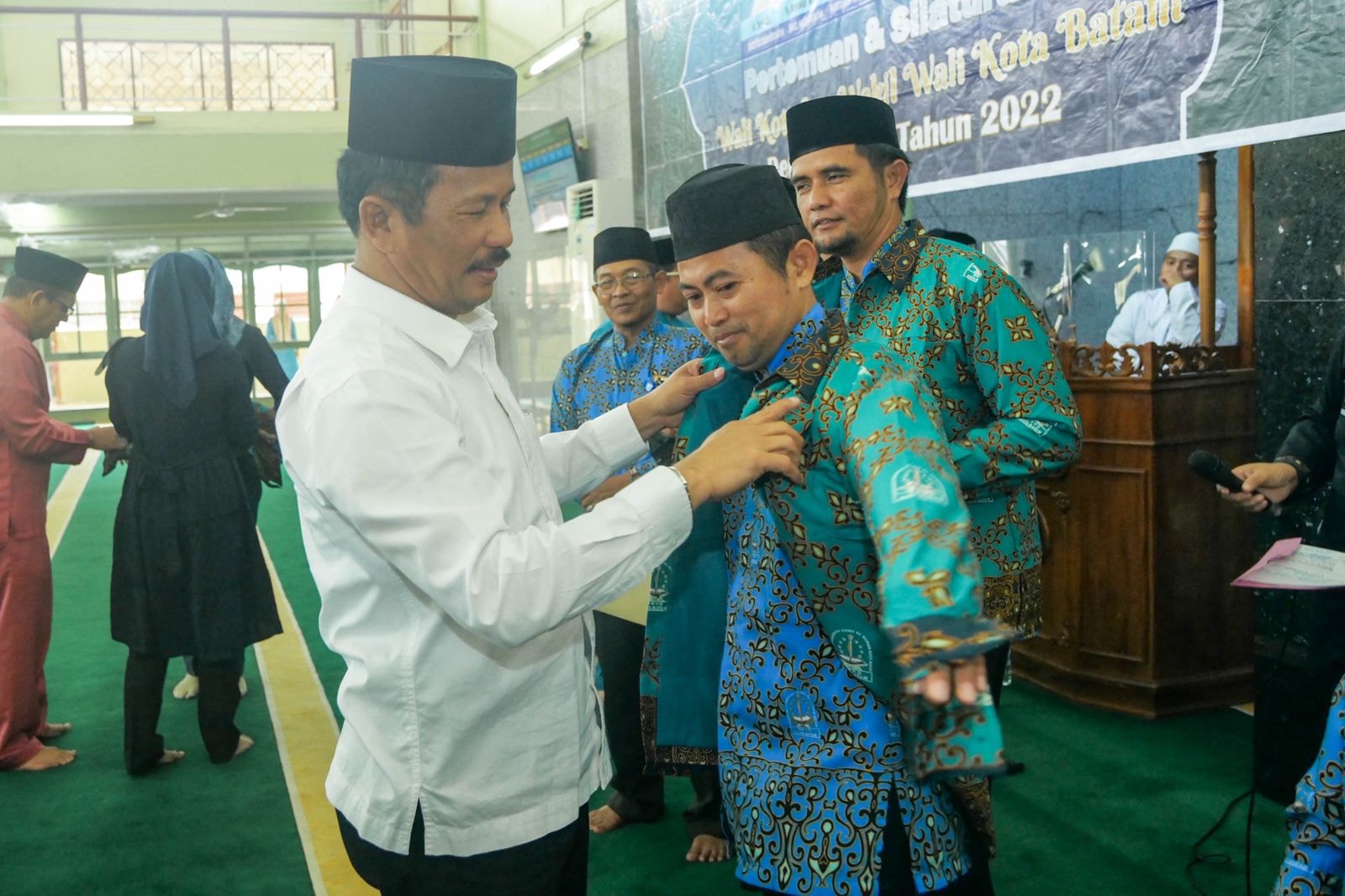 WALI Kota Batam H Muhammad Rudi (HMR), memasangkan seragam secara simbolis kepada perwakilan guru TPQ se-Kecamatan Sekupang, Rabu (14/12/2022) pagi.