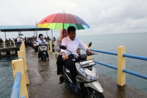 Marlin Payungi HMR di Tengah Dera Hujan Saat ke Lokasi Musrenbang di Galangbaru