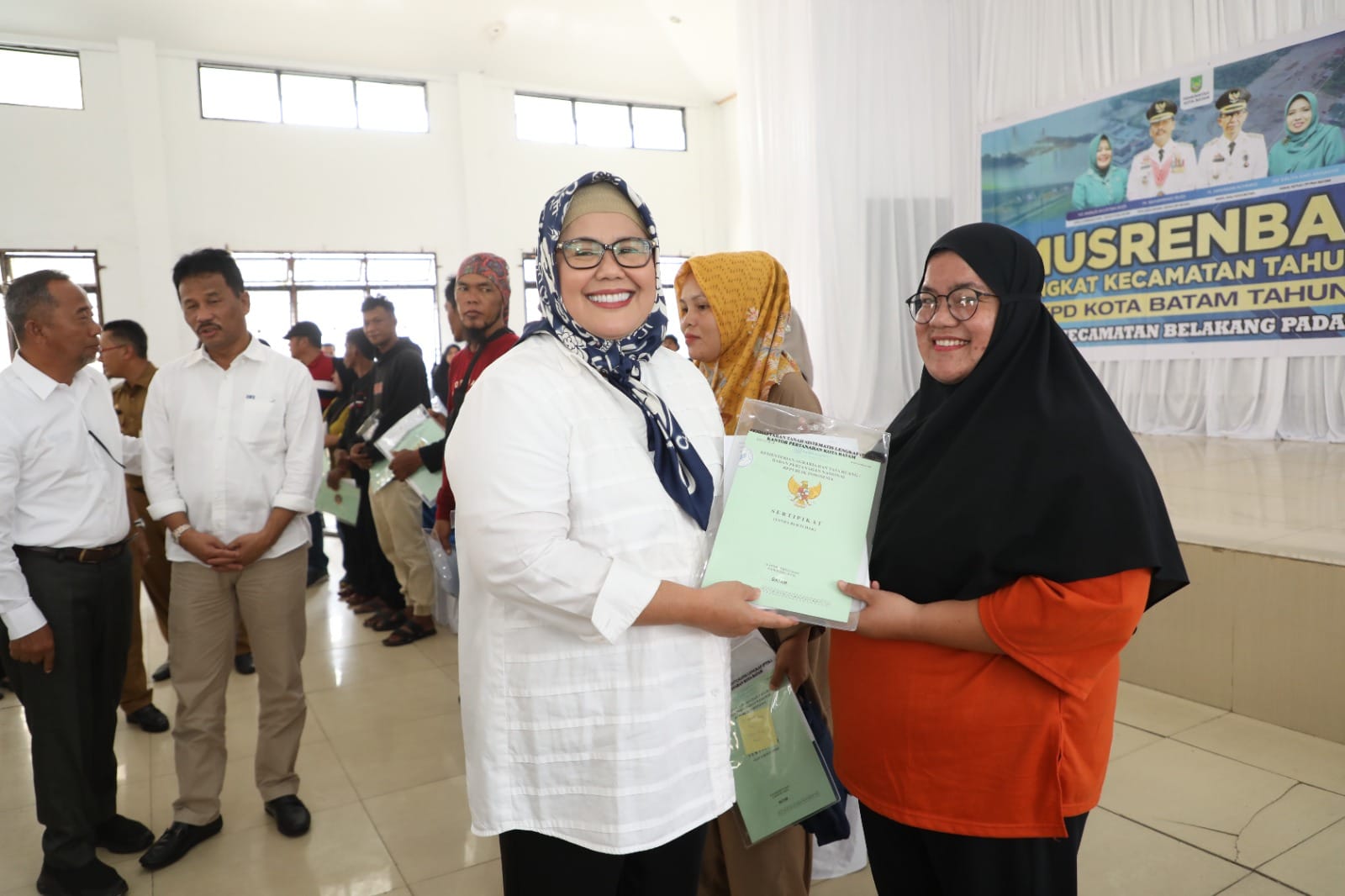 WAGUB Marlin diiring Wali Kota Batam/Kepala Badan Pengusahaan Batam H Muhammad Rudi (HMR), menyerahkan sertifikat tanah kepada warga di sela menghadiri Musrenbang Kecamatan Belakangpadang, Senin (6/2/2023) pagi.